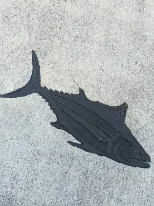 A second sidewalk casting beside it, a long tuna with its fins picked out in relief.