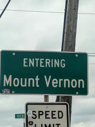 A green road sign on a timber pole reading Entering Mount Vernon.