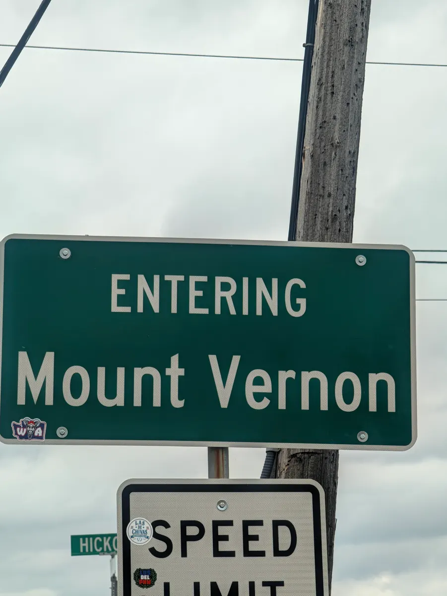 A green road sign on a timber pole reading Entering Mount Vernon.