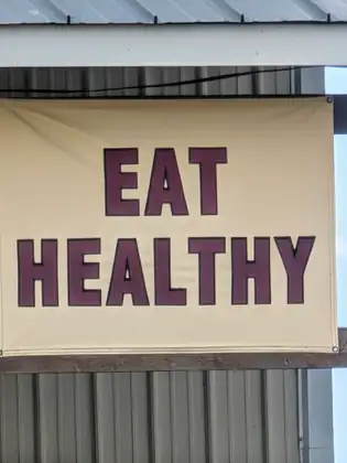 A large banner on the side of a metal barn reading EAT HEALTHY in tall dark letters.