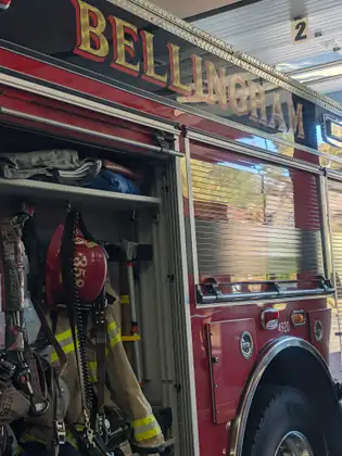 The side of a Bellingham fire engine, the city name in gold lettering above the open equipment bay.