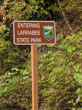 A brown park sign in the undergrowth reading Entering Larrabee State Park.