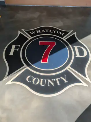 The Whatcom County Fire District 7 emblem, a black Maltese cross with a red 7, set into a polished floor.