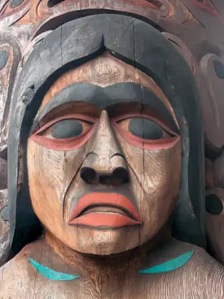 A close view of a carved and painted wooden face, with red lips and touches of turquoise.