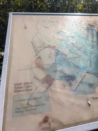 A weathered, sun-faded map panel of the Swan Lake Watershed, showing Swan Lake, Christmas Hill and the Lochside Regional Trail.