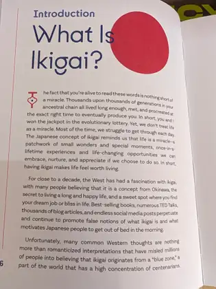 An open book at a page headed 'Introduction' and 'What Is Ikigai?' in large navy letters beside a red circle, above several paragraphs of text about the Japanese idea of ikigai.