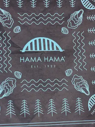 A dark paper wrapper printed in pale blue with oysters, waves and trees around the Hama Hama logo and “Est. 1922.”