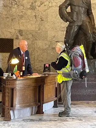 Jeana speaks with a man at a wooden reception desk inside the Capitol.