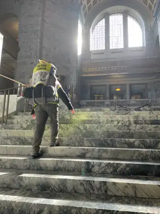 Jeana walks up marble stairs beneath a tall arched window inside the Capitol.