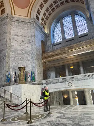 Jeana stands in the spacious marble rotunda, with flags, balconies and an arched window around her.
