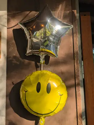 A gold star balloon and a yellow smile balloon hang together in a celebration of the finished walk.