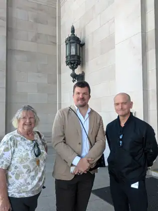 Jeana stands with two men outside the Capitol, one in a tan jacket and one in black.