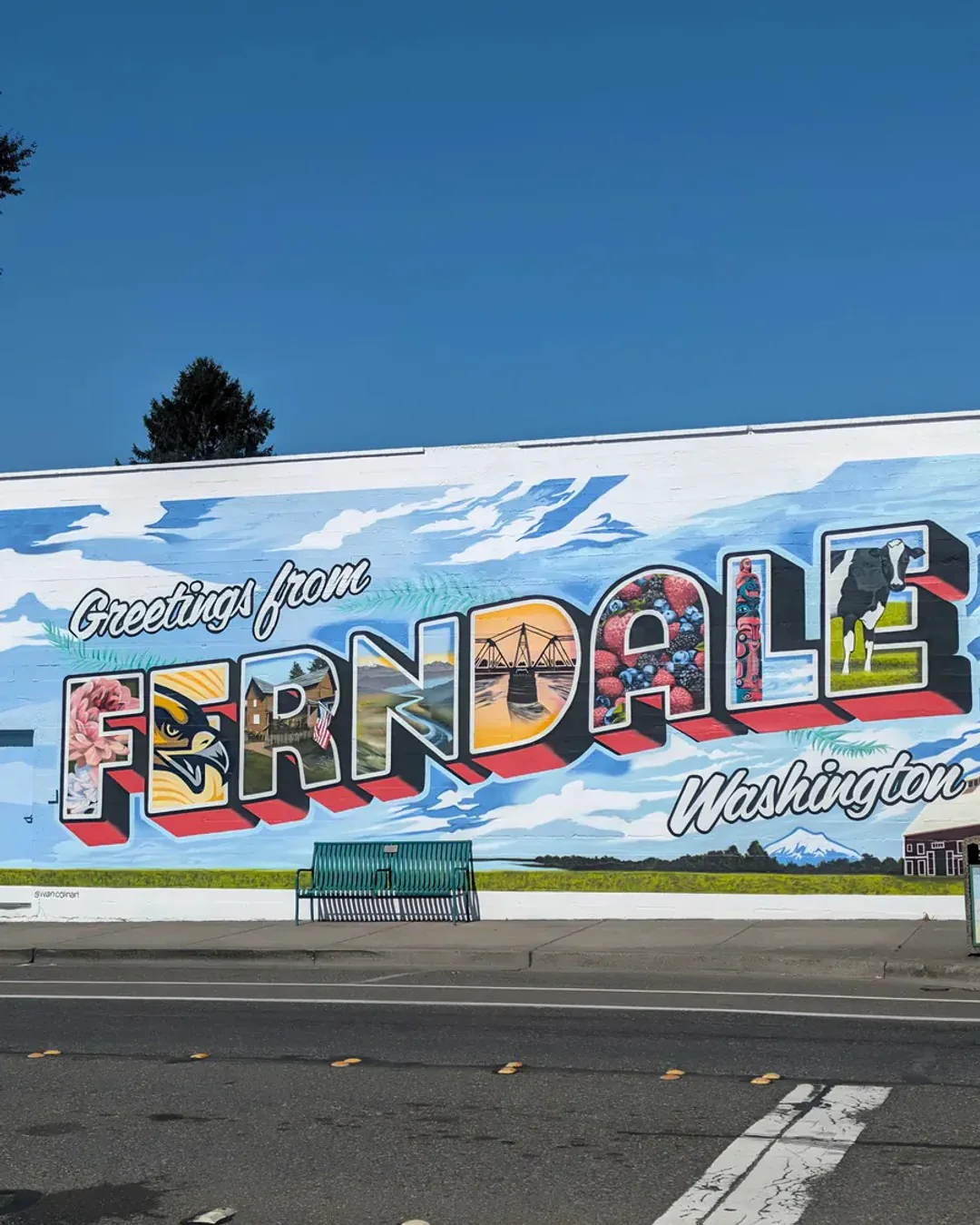 A mural the length of a building reading Greetings from Ferndale, Washington, each big letter filled with a local scene.