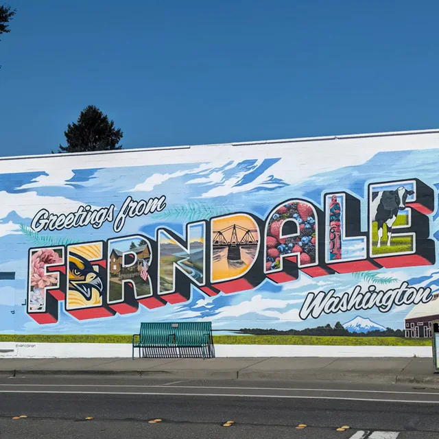A mural the length of a building reading Greetings from Ferndale, Washington, each big letter filled with a local scene.